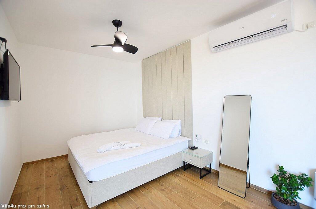 כינר סוויטות יוקרה - מיטה זוגית מול טלוויזיה ולצד מראת גוף